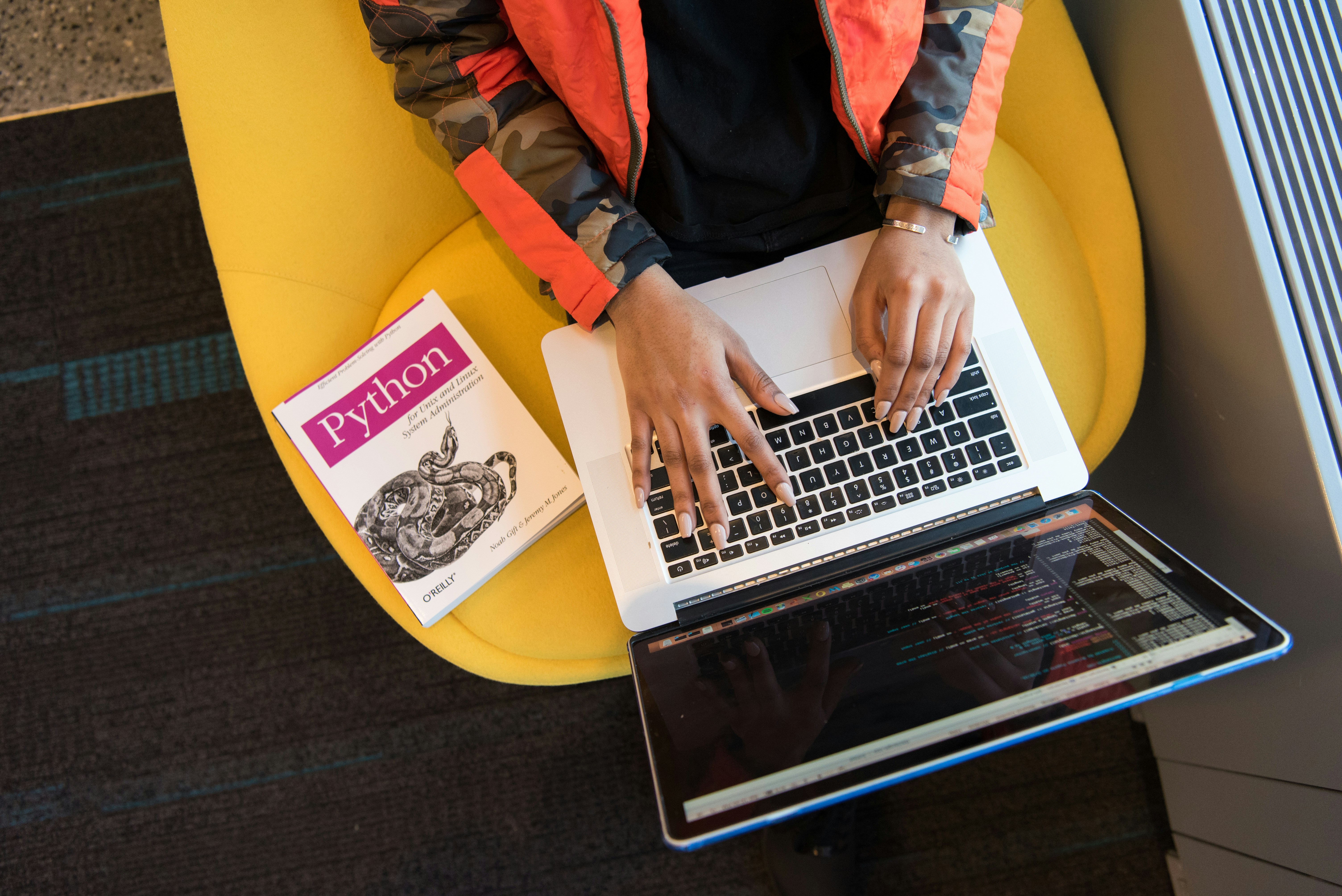 A picture of a woman with a laptop working on code.